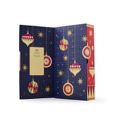Geöffneter marineblauer Whittard Tee-Adventskalender 2026 mit goldenen Weihnachtskugelillustrationen