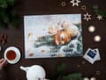 Flat TeeGschwendner advent calendar of numbered doors over gold baubles and fir, with a Salzcaramel sample packet, a teapot and a cup of tea.