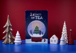 Adagio Teas 24 Days of Tea Kalender neben kleinen Holzbäumen und Häusern
