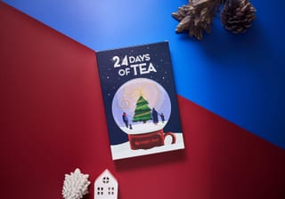Adagio Teas 24 Days of Tea Kalender auf rotem Hintergrund mit Tannenzapfen