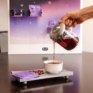 Hånd, der skænker te ved siden af Paper & Tea-adventskalenderen for 2026