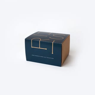 Geschlossene marineblaue Rishi Premium-Box mit einer Kollektion loser Tees