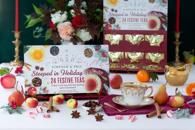 Simpson & Vail card reading Steeped in Holiday Magic and 24 Festive Teas, in front of an open red and gold drawer calendar, with a cup, fruit and spices on the table.
