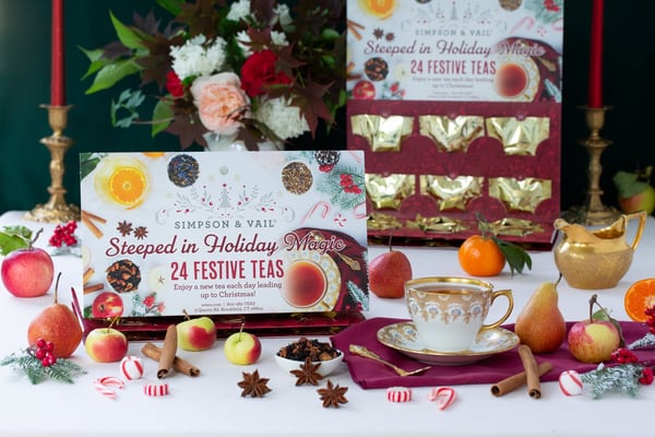 Simpson & Vail card reading Steeped in Holiday Magic and 24 Festive Teas, in front of an open red and gold drawer calendar, with a cup, fruit and spices on the table.